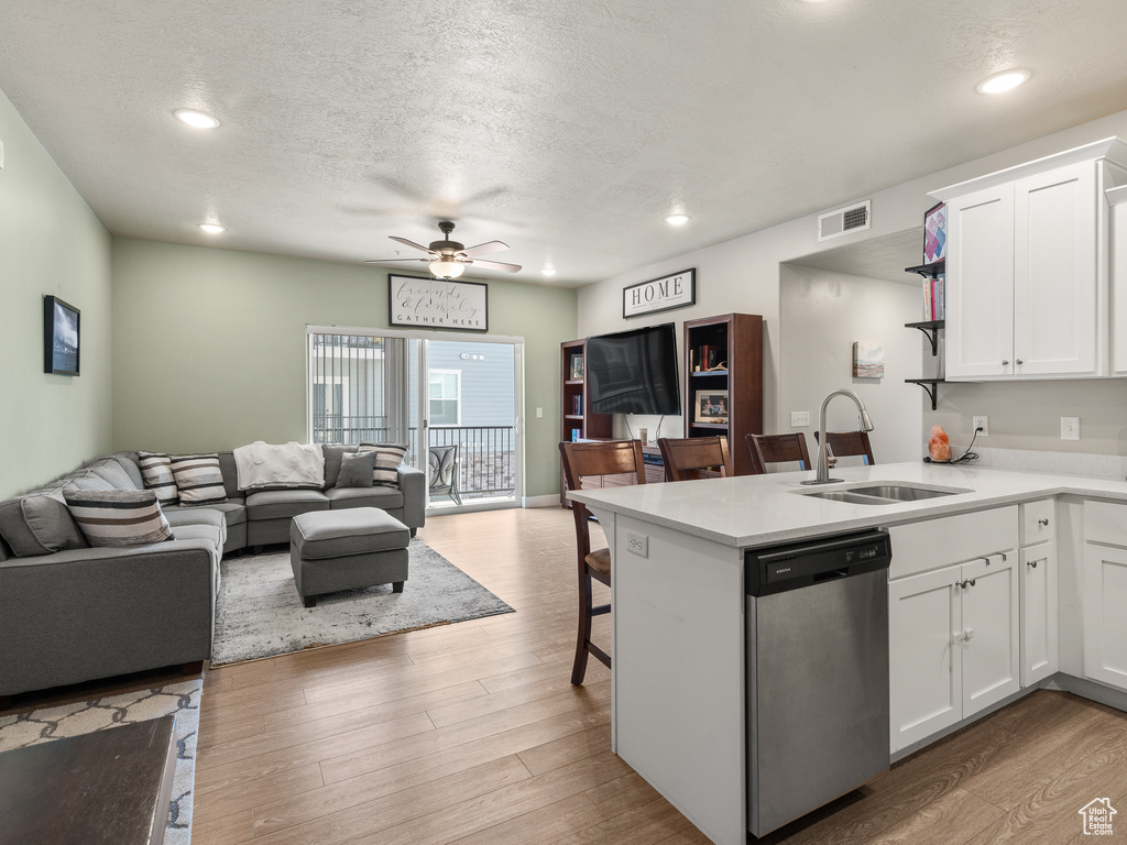 Kitchen featuring white cabinets, light hardwood / wood-style floors, dishwasher, and kitchen peninsula