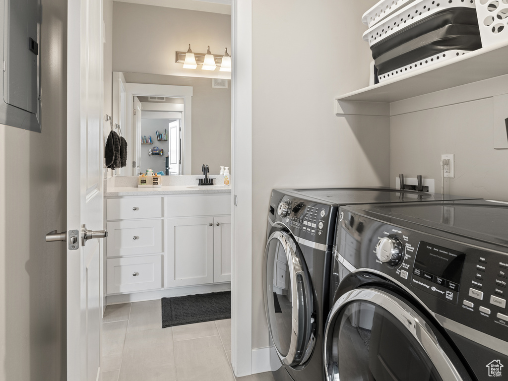 Laundry room featuring sink, light tile floors, and separate washer and dryer