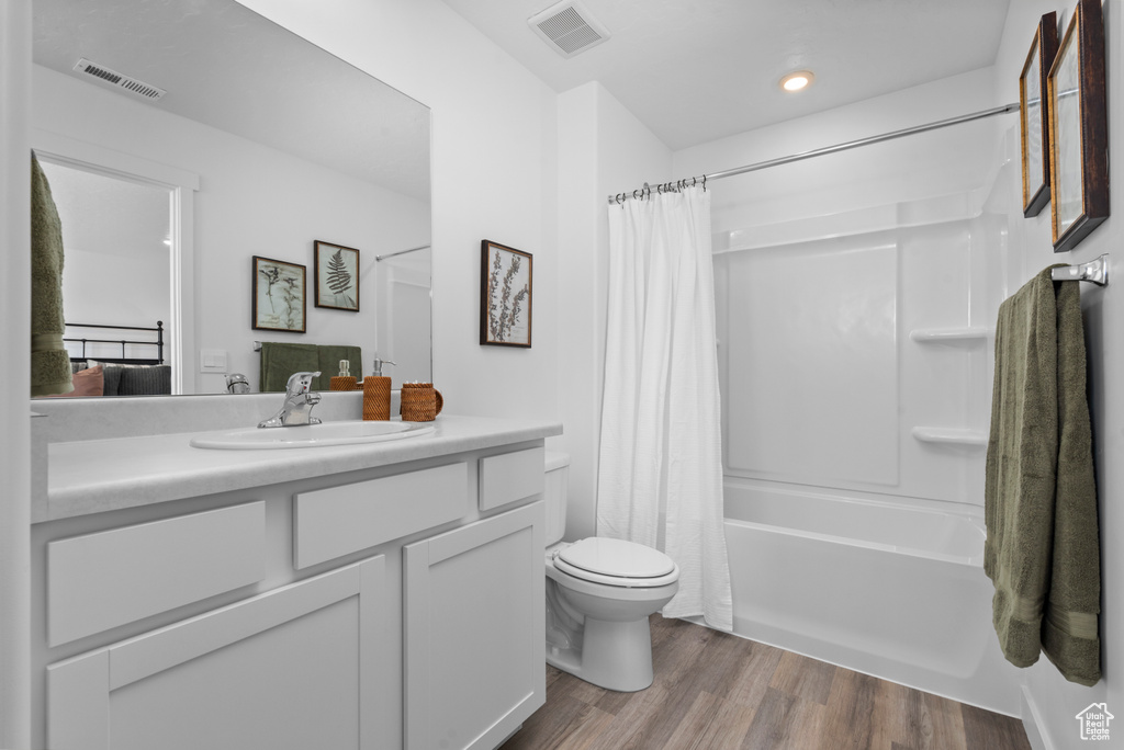 Full bathroom featuring hardwood / wood-style floors, vanity, toilet, and shower / bathtub combination with curtain