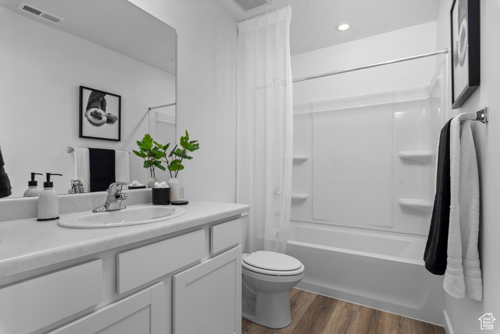 Full bathroom featuring wood-type flooring, washtub / shower combination, vanity, and toilet