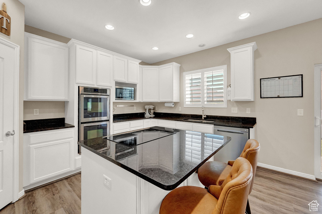 Kitchen featuring a kitchen island, light hardwood / wood-style flooring, white cabinetry, and stainless steel appliances