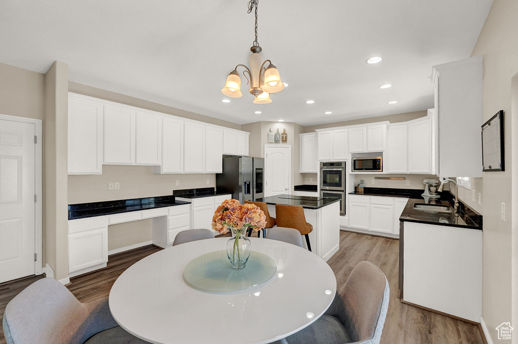 Kitchen featuring appliances with stainless steel finishes, a center island, light hardwood / wood-style flooring, and pendant lighting