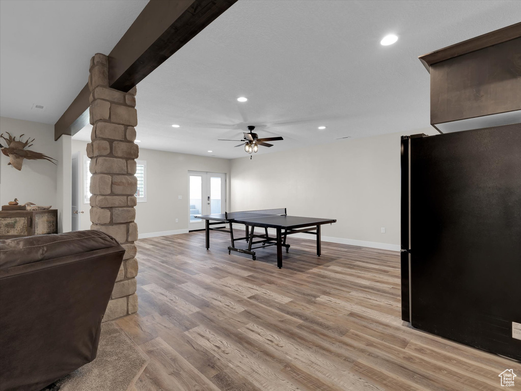 Rec room featuring beamed ceiling, ceiling fan, light hardwood / wood-style floors, decorative columns, and french doors