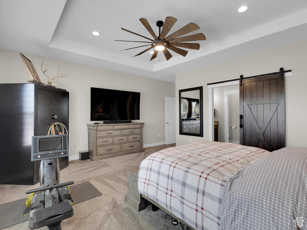 Bedroom featuring light colored carpet, ceiling fan, a raised ceiling, and a barn door