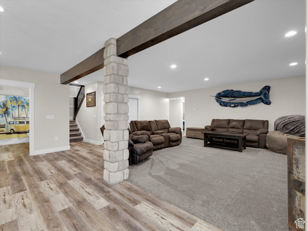 Living room featuring beam ceiling, decorative columns, and light wood-type flooring