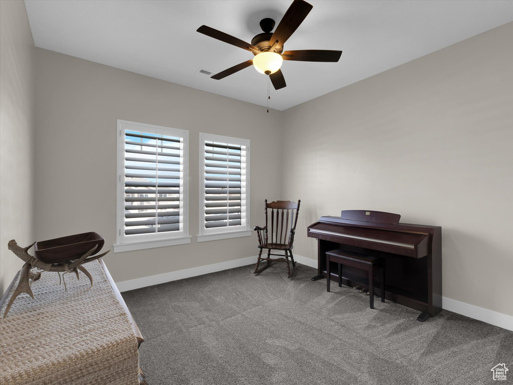Living area featuring ceiling fan and dark colored carpet