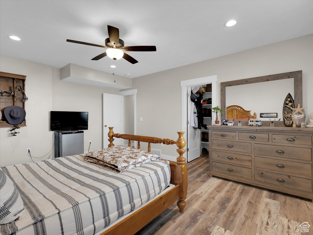 Bedroom featuring a spacious closet, a closet, light hardwood / wood-style floors, and ceiling fan