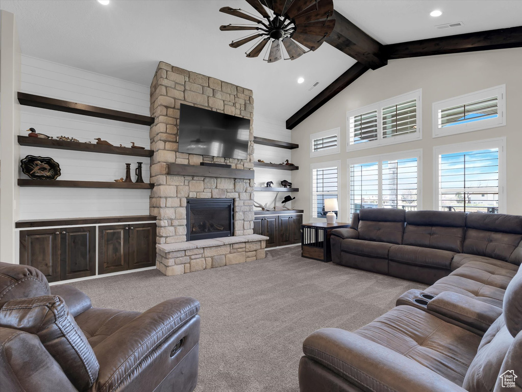 Carpeted living room featuring vaulted ceiling with beams and a stone fireplace