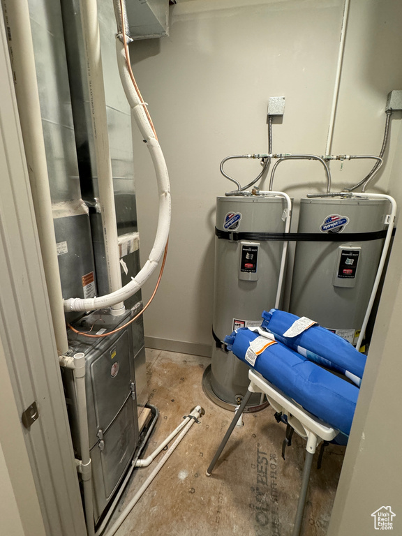 Utility room featuring strapped water heater and electric water heater