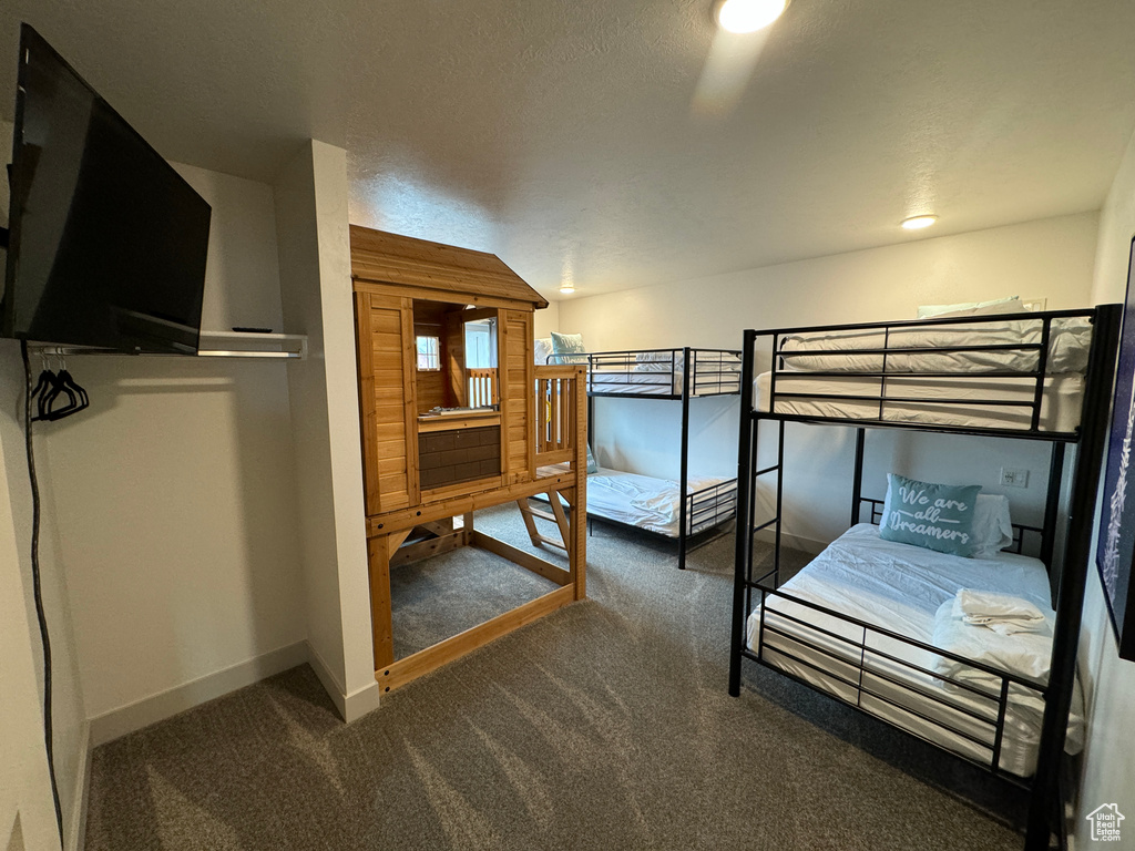 Carpeted bedroom featuring a textured ceiling and vaulted ceiling