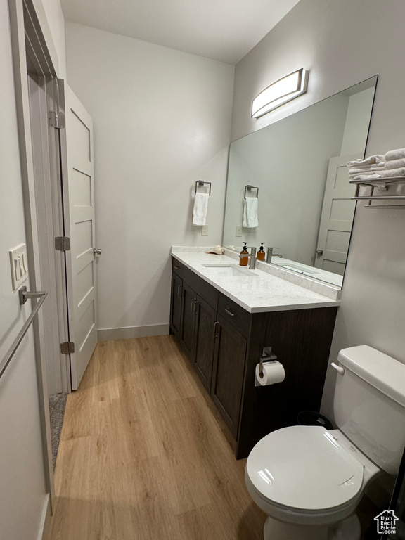 Bathroom with hardwood / wood-style floors, vanity, and toilet