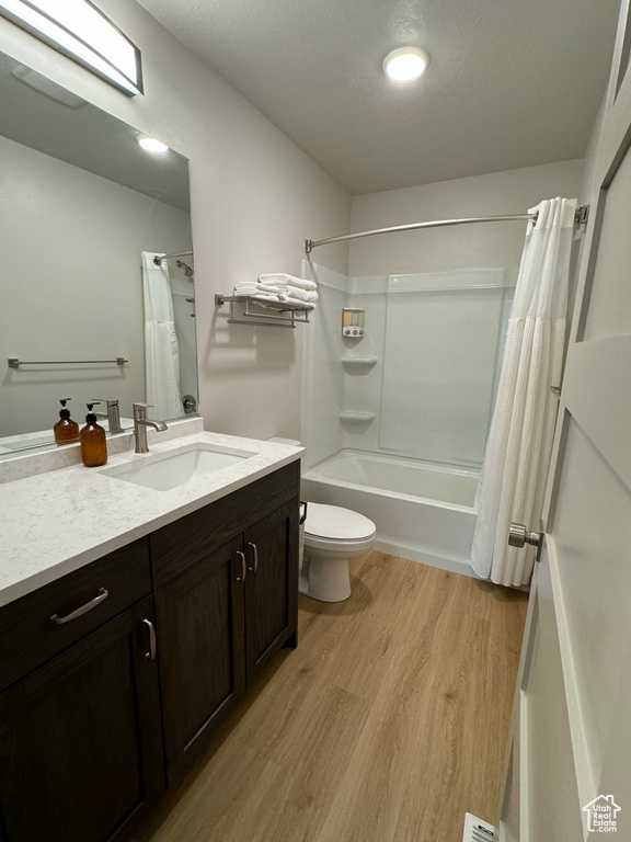 Full bathroom featuring hardwood / wood-style flooring, shower / tub combo, toilet, and vanity