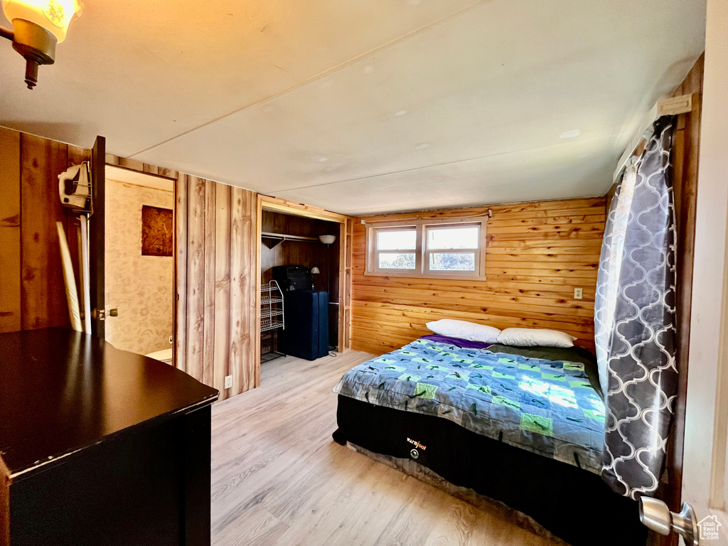 Bedroom featuring light hardwood / wood-style flooring and wooden walls