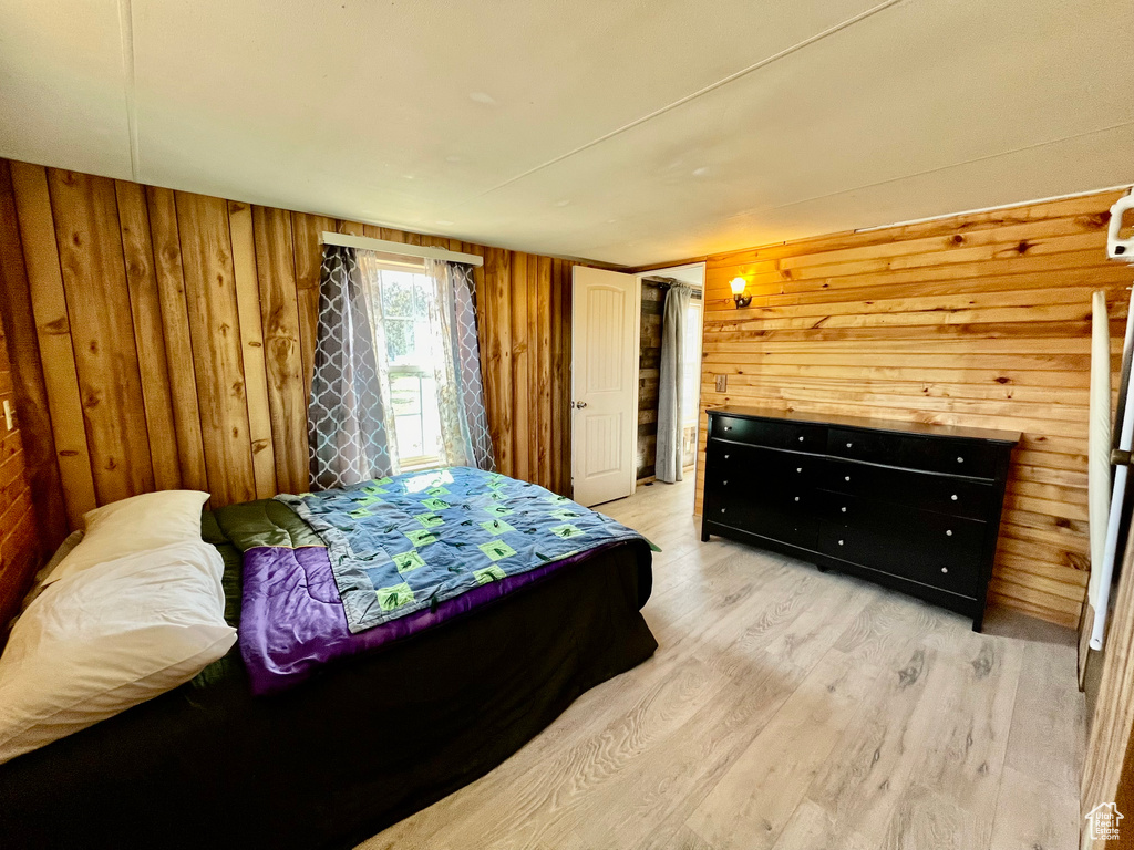 Bedroom with wood walls and light hardwood / wood-style flooring