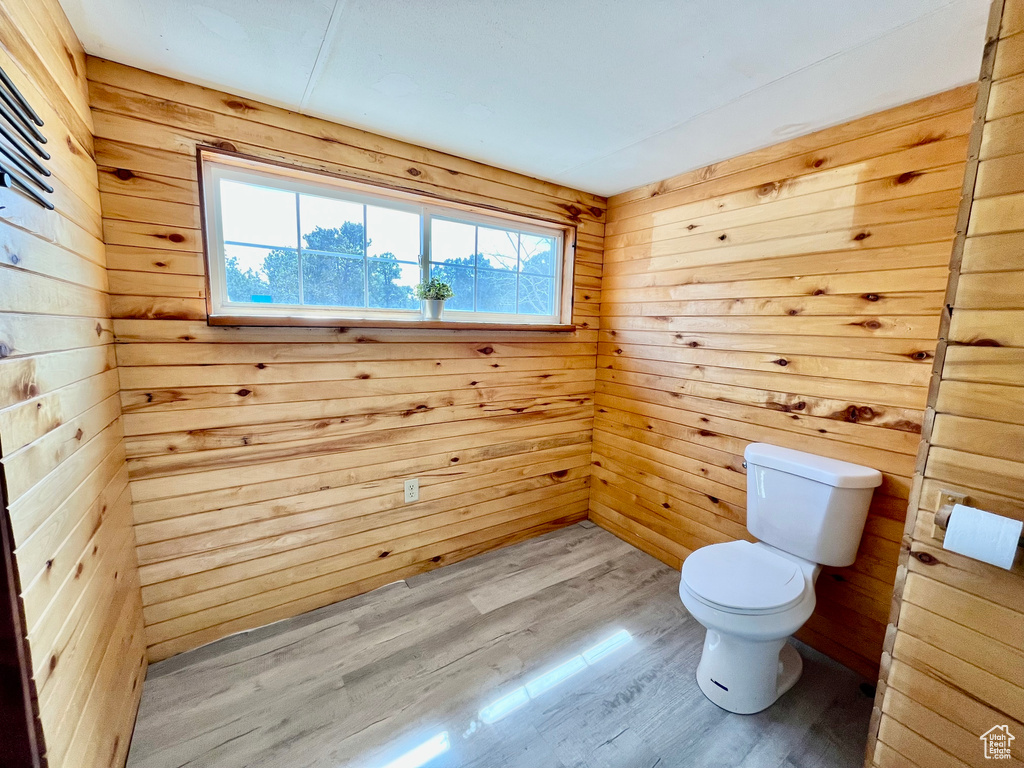 Bathroom featuring wood walls, toilet, and hardwood / wood-style floors
