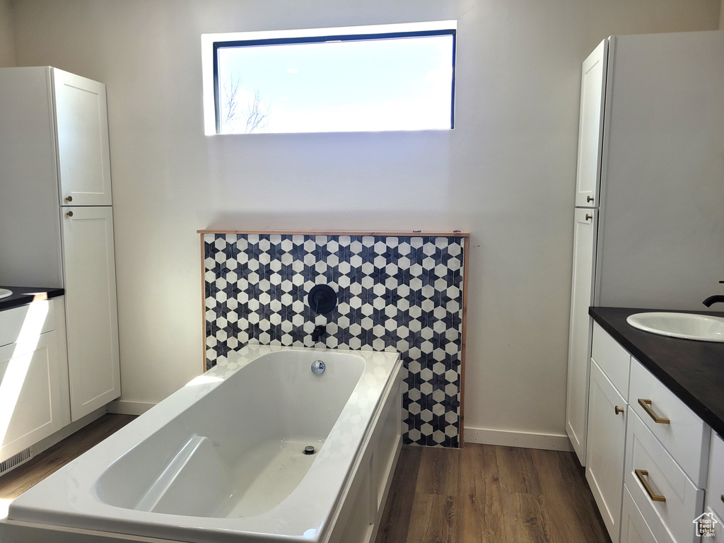 Bathroom featuring a tub, vanity, and hardwood / wood-style flooring