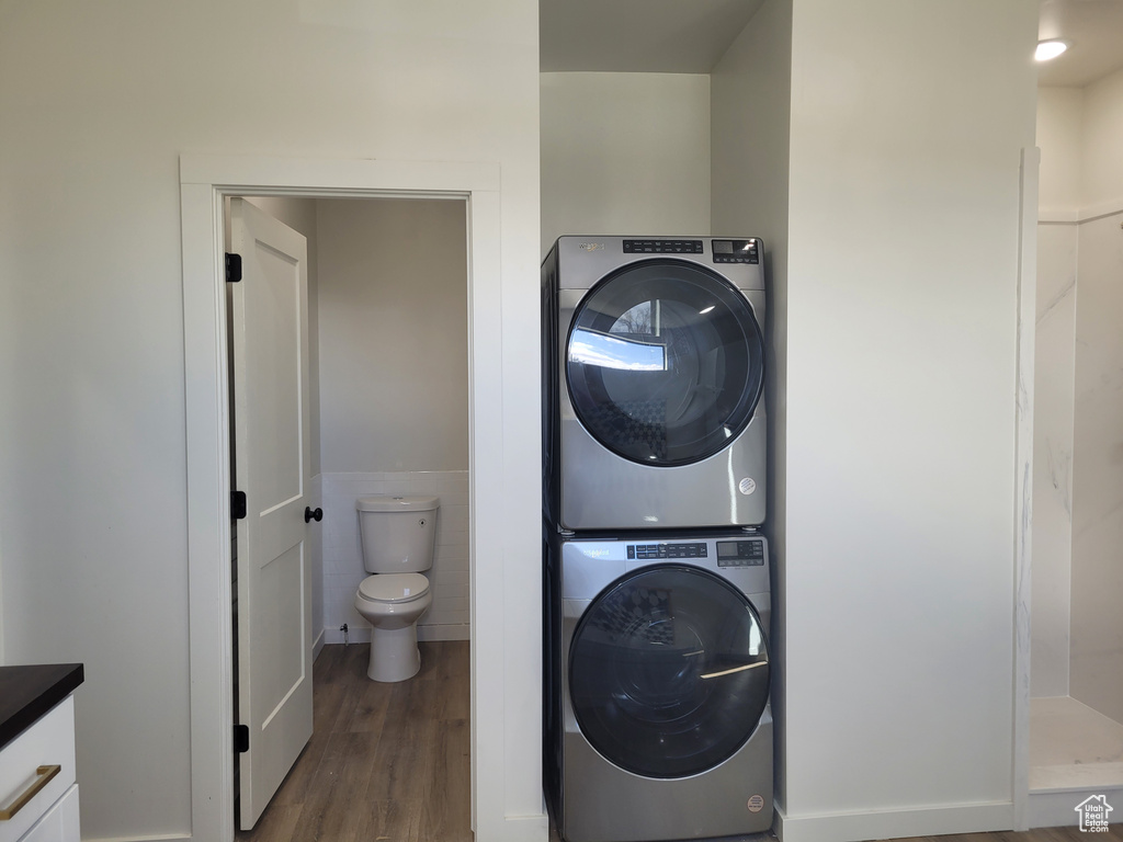 Laundry area with dark hardwood / wood-style floors and stacked washer and dryer