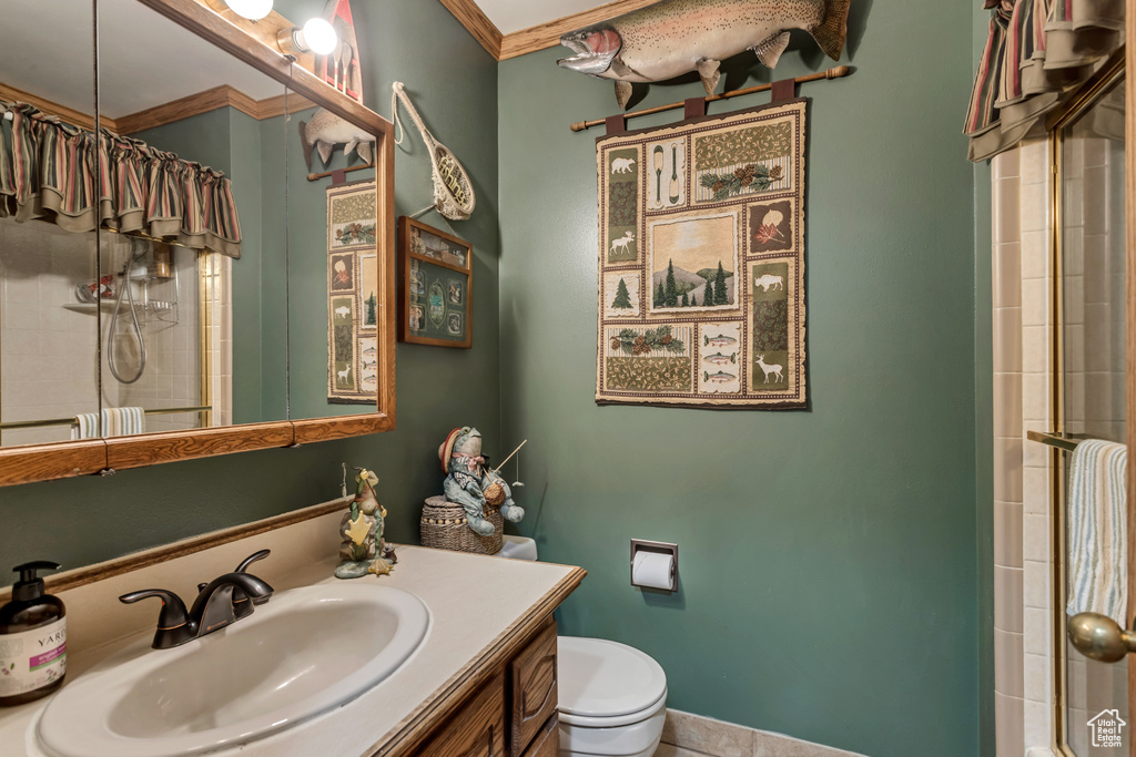 Bathroom featuring vanity with extensive cabinet space, crown molding, and toilet