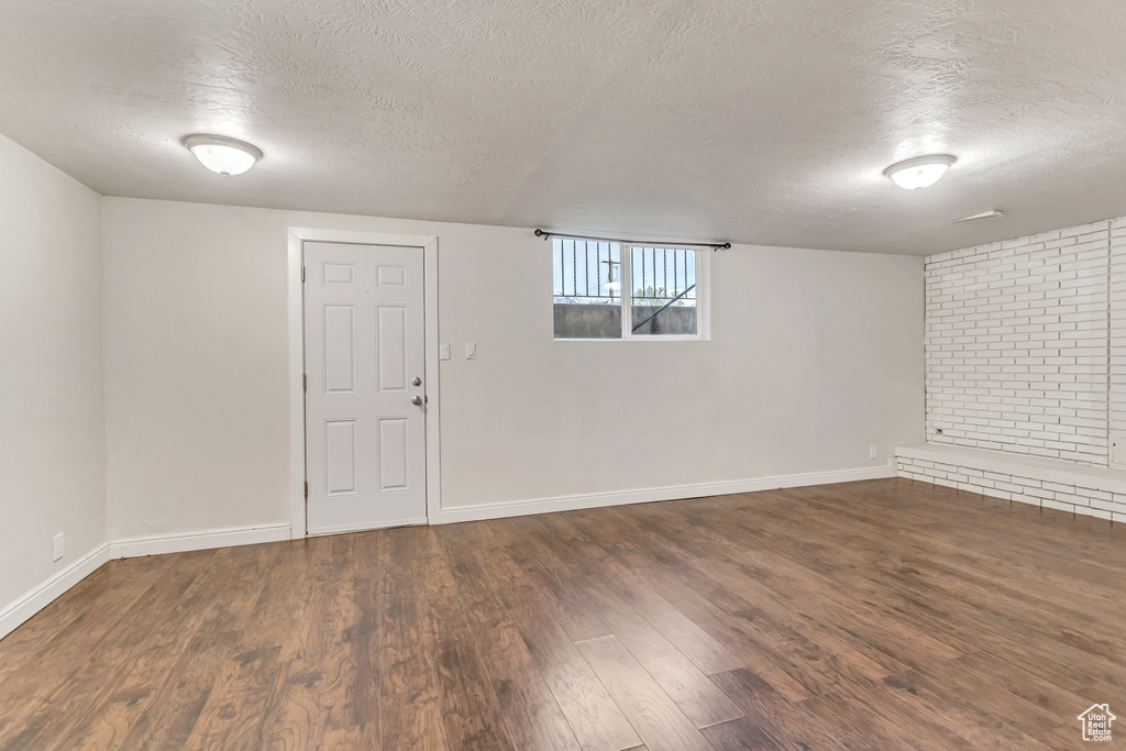 Basement with dark hardwood / wood-style floors and a textured ceiling