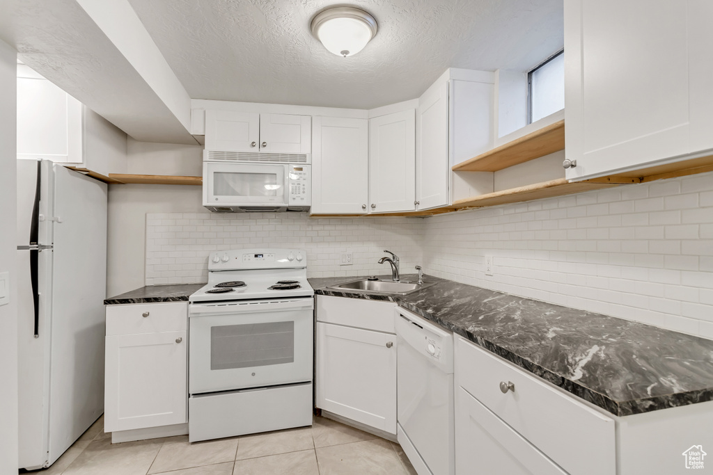 Kitchen featuring white cabinets, white appliances, backsplash, sink, and a textured ceiling