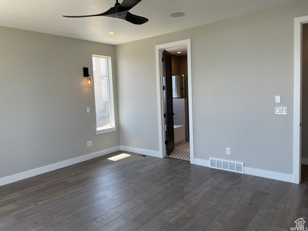 Unfurnished room featuring ceiling fan and dark wood-type flooring