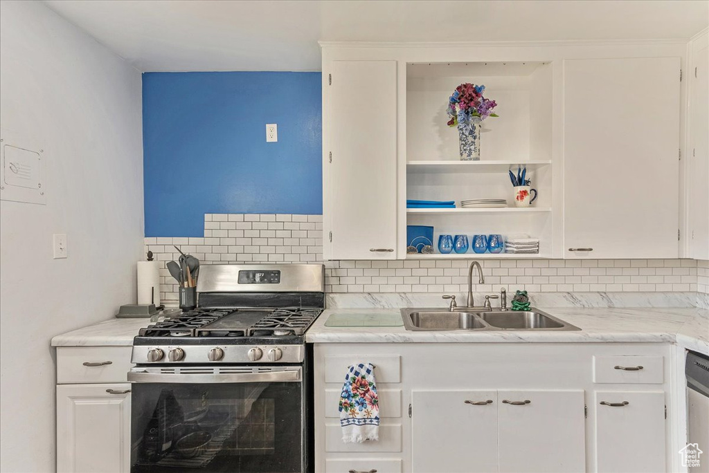 Kitchen featuring white cabinets, sink, appliances with stainless steel finishes, and backsplash