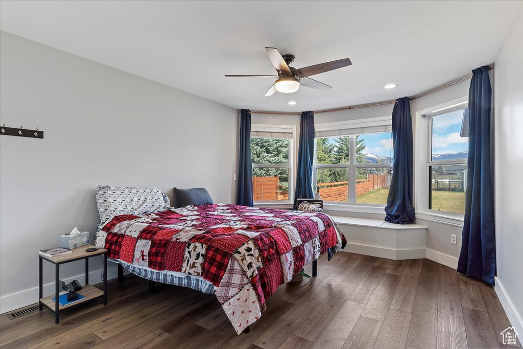 Bedroom featuring dark hardwood / wood-style flooring, multiple windows, and ceiling fan