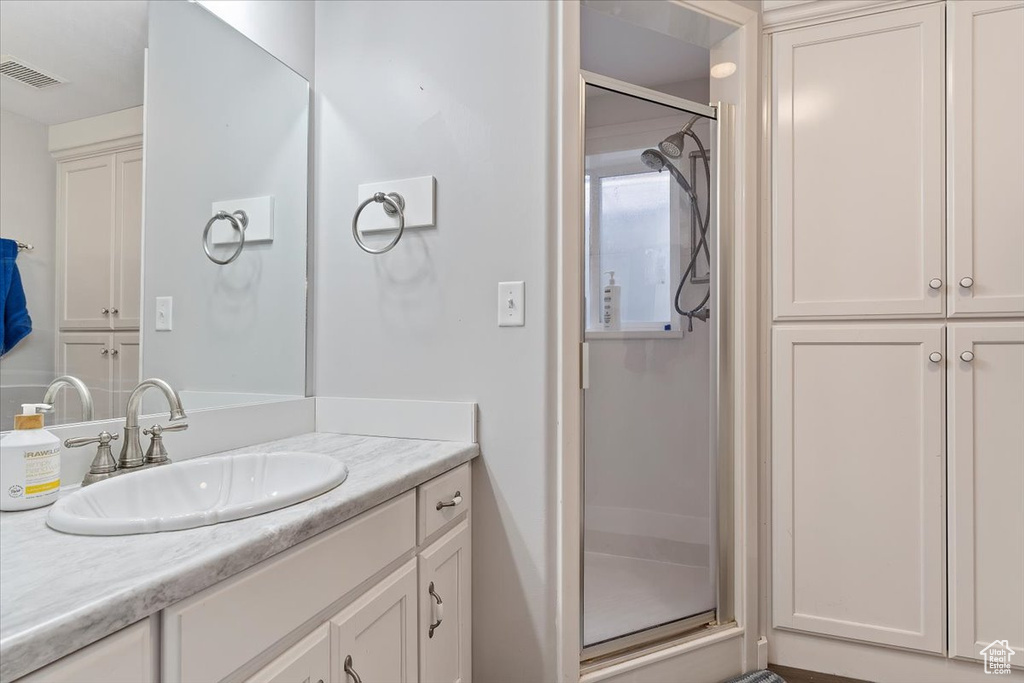 Bathroom featuring an enclosed shower and vanity with extensive cabinet space
