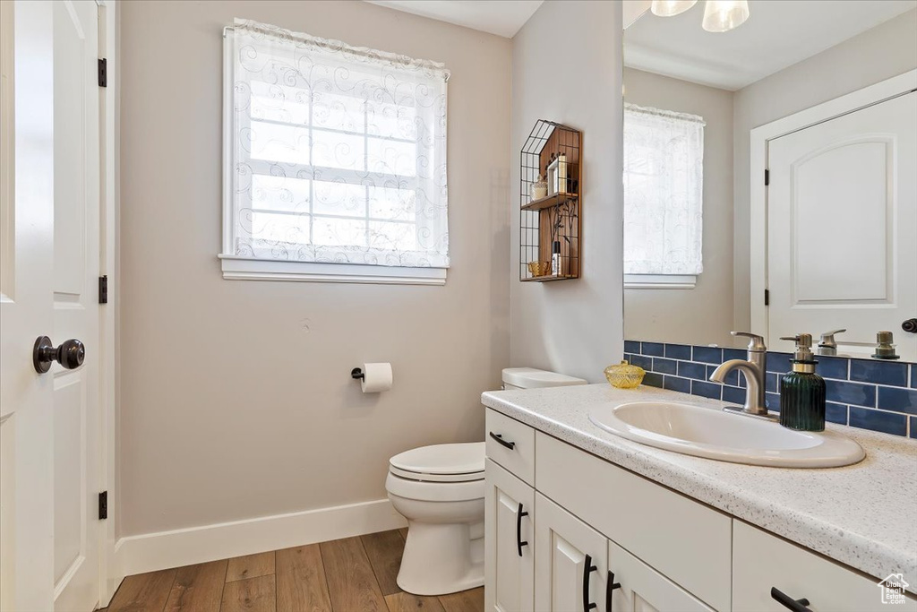 Bathroom with a healthy amount of sunlight, hardwood / wood-style flooring, toilet, and vanity