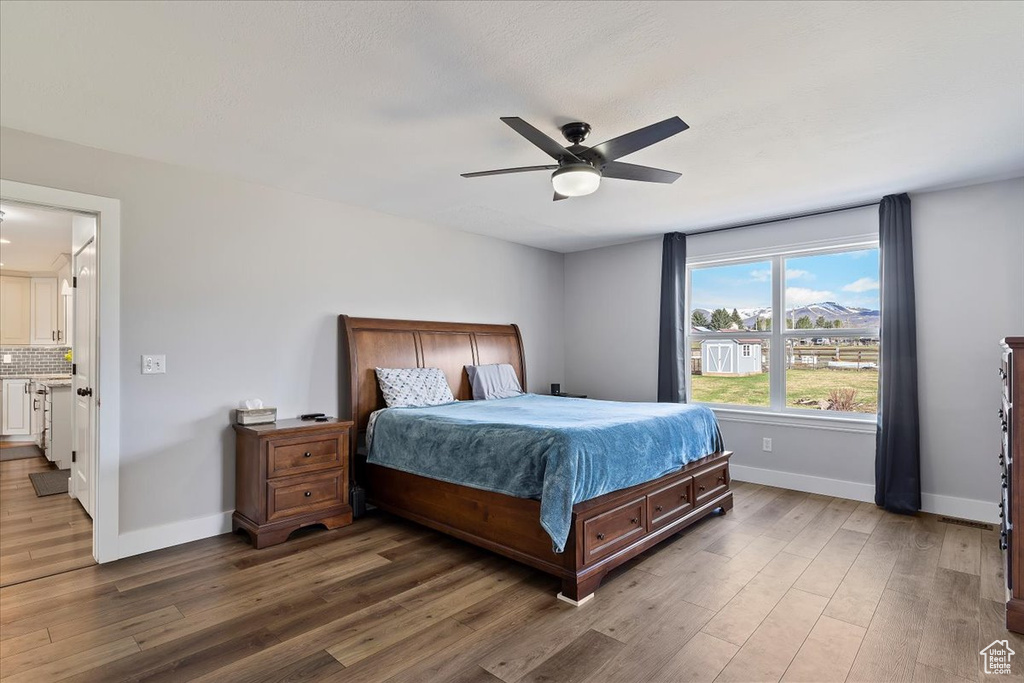 Bedroom with dark hardwood / wood-style flooring, ceiling fan, and ensuite bath