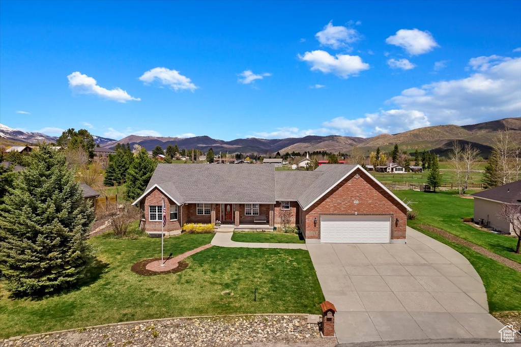 Ranch-style home with a front yard, a mountain view, and a garage