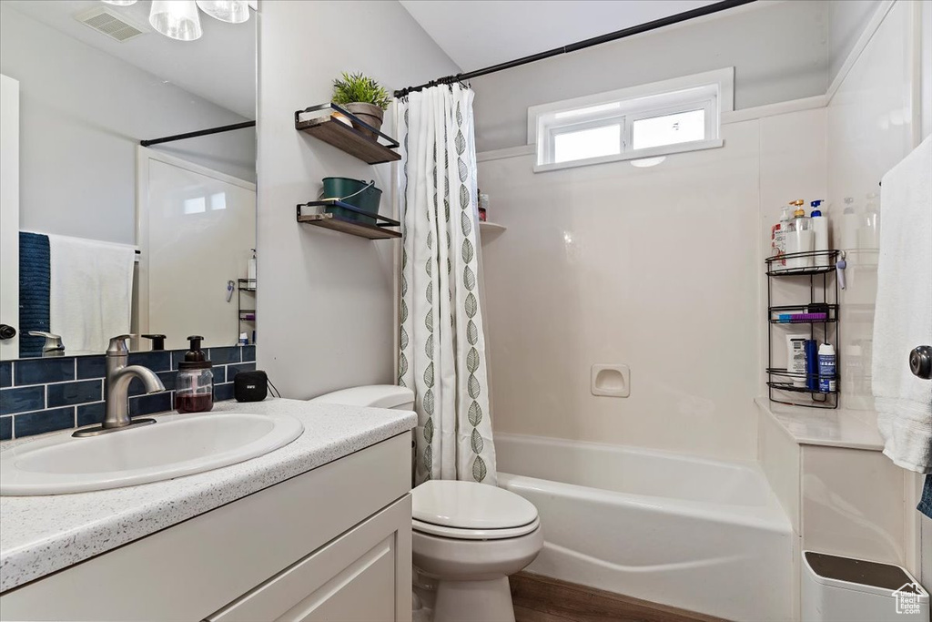 Full bathroom featuring backsplash, shower / tub combo with curtain, toilet, wood-type flooring, and vanity
