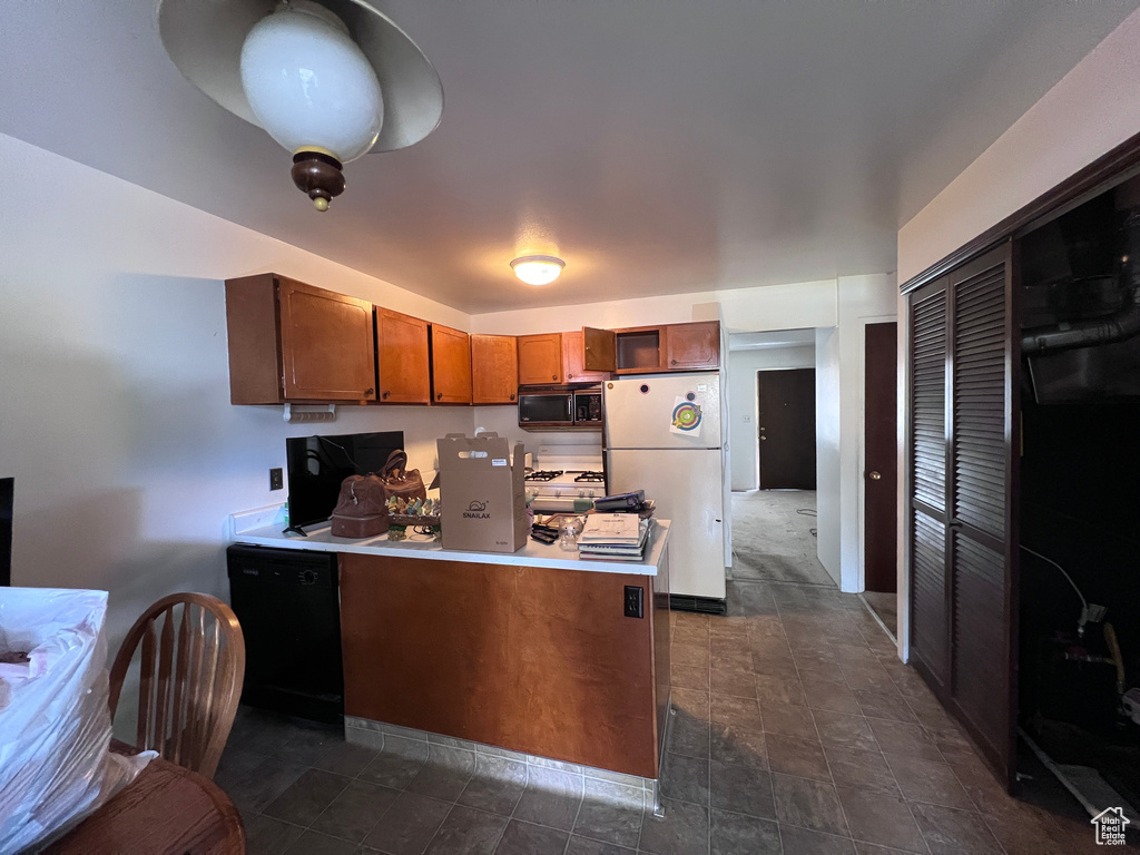 Kitchen featuring kitchen peninsula, dark tile floors, white fridge, and dishwasher