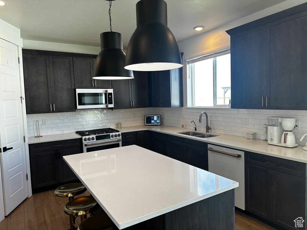 Kitchen featuring a kitchen breakfast bar, dark hardwood / wood-style floors, stainless steel appliances, sink, and a kitchen island