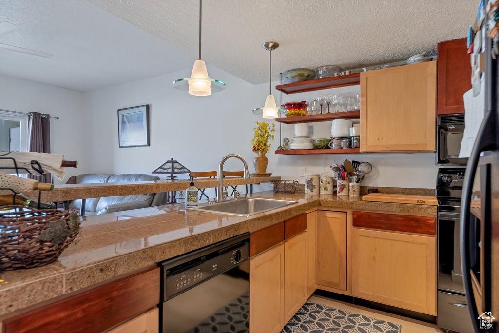 Kitchen featuring a textured ceiling, sink, dishwashing machine, kitchen peninsula, and pendant lighting