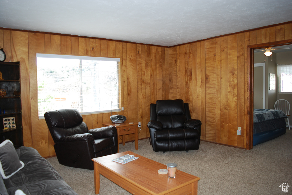 Living room featuring wooden walls, plenty of natural light, light carpet, and ceiling fan