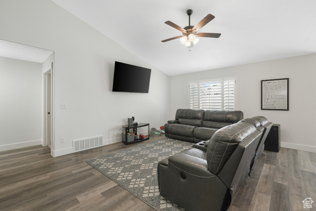 Living room with dark wood-type flooring, ceiling fan, and vaulted ceiling