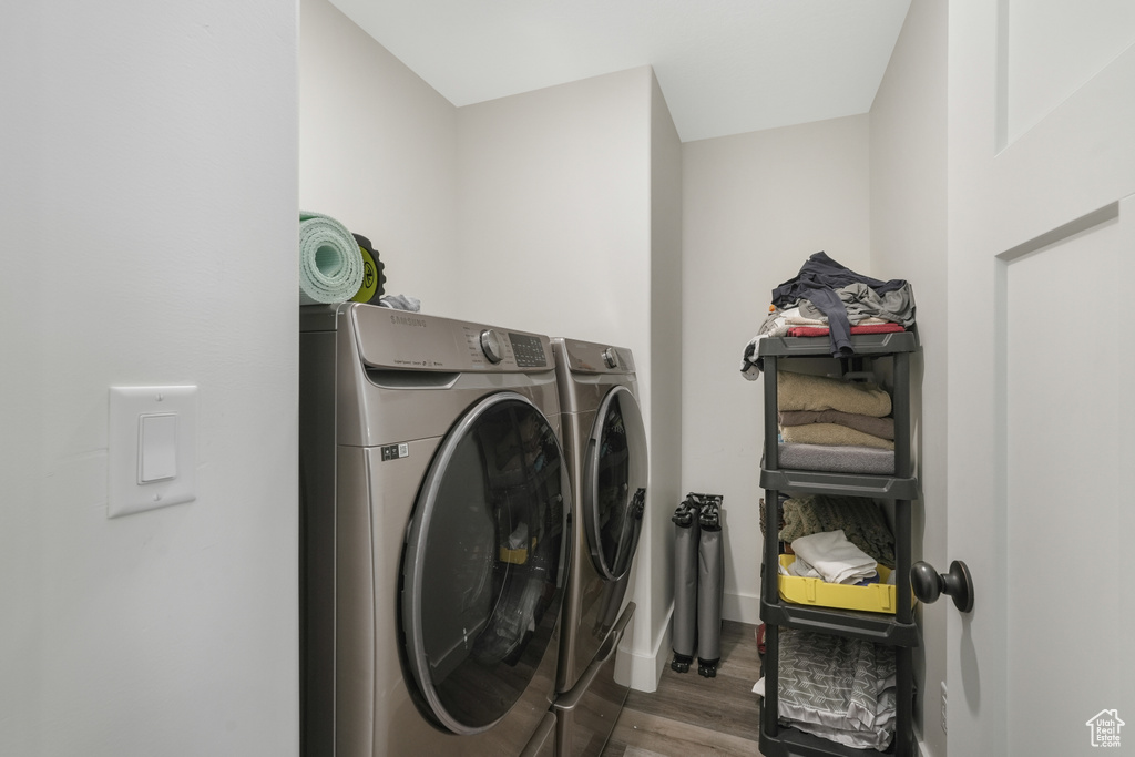 Clothes washing area with dark hardwood / wood-style flooring and washing machine and dryer