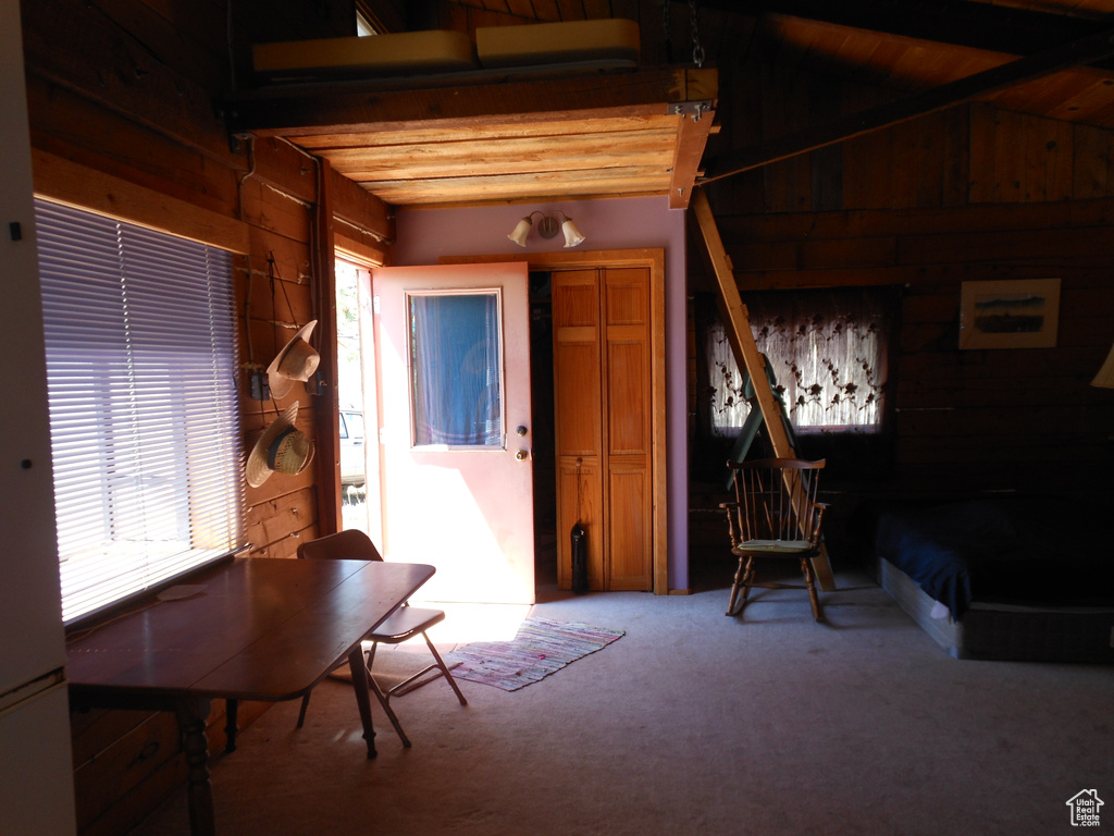Interior space featuring wood walls, light colored carpet, and beamed ceiling
