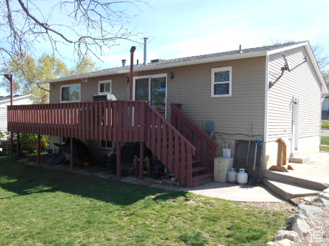 Rear view of house with a wooden deck and a lawn