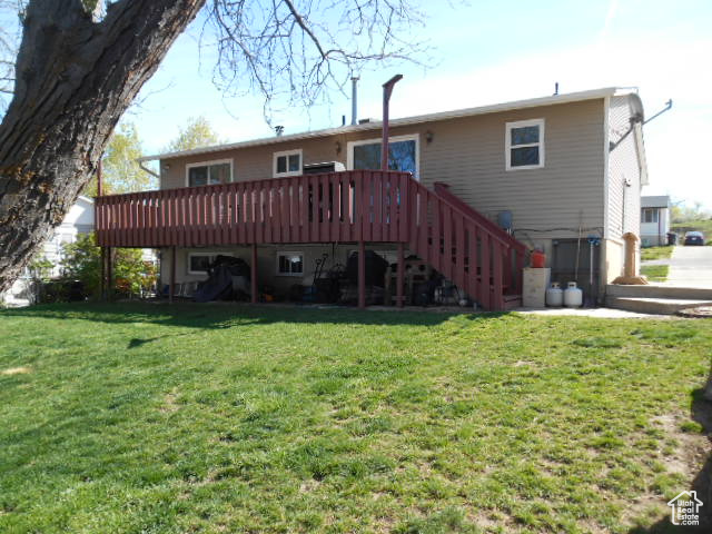 Back of house with a deck and a yard