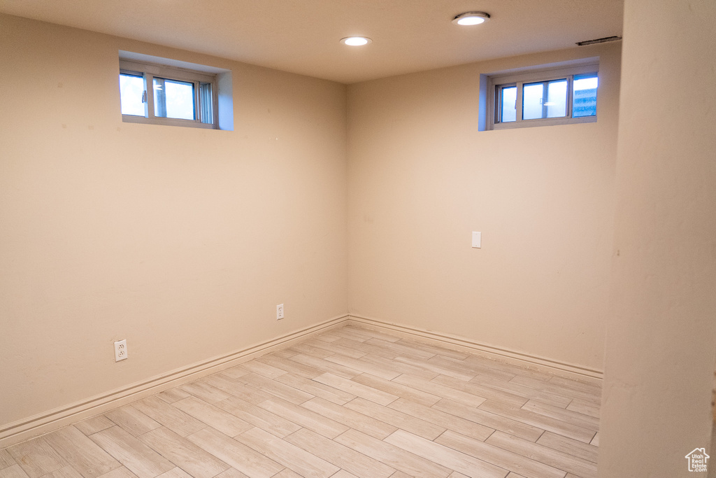 Basement featuring a healthy amount of sunlight and light hardwood / wood-style flooring