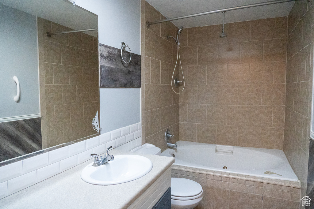 Full bathroom featuring tiled shower / bath combo, a textured ceiling, vanity, and toilet