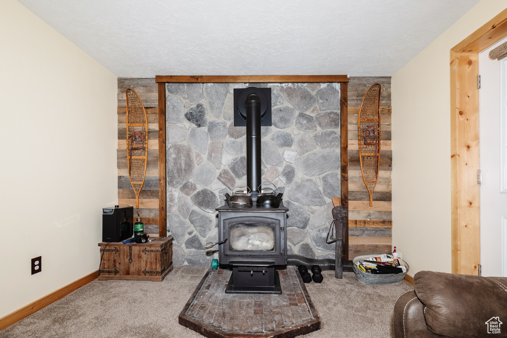 Carpeted living room featuring a wood stove and a textured ceiling