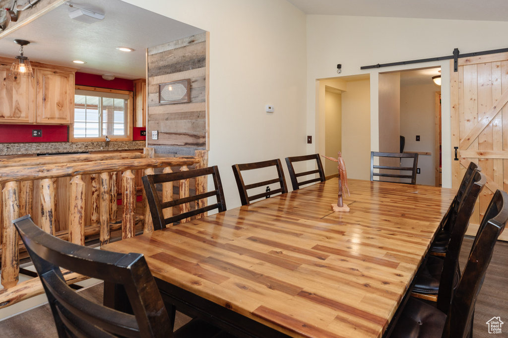 Dining space with vaulted ceiling, a barn door, and hardwood / wood-style floors