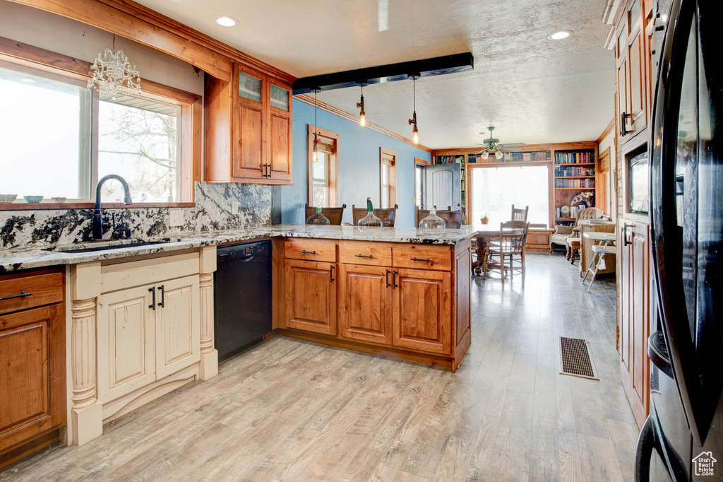 Kitchen featuring ceiling fan, black appliances, light hardwood / wood-style flooring, pendant lighting, and light stone countertops