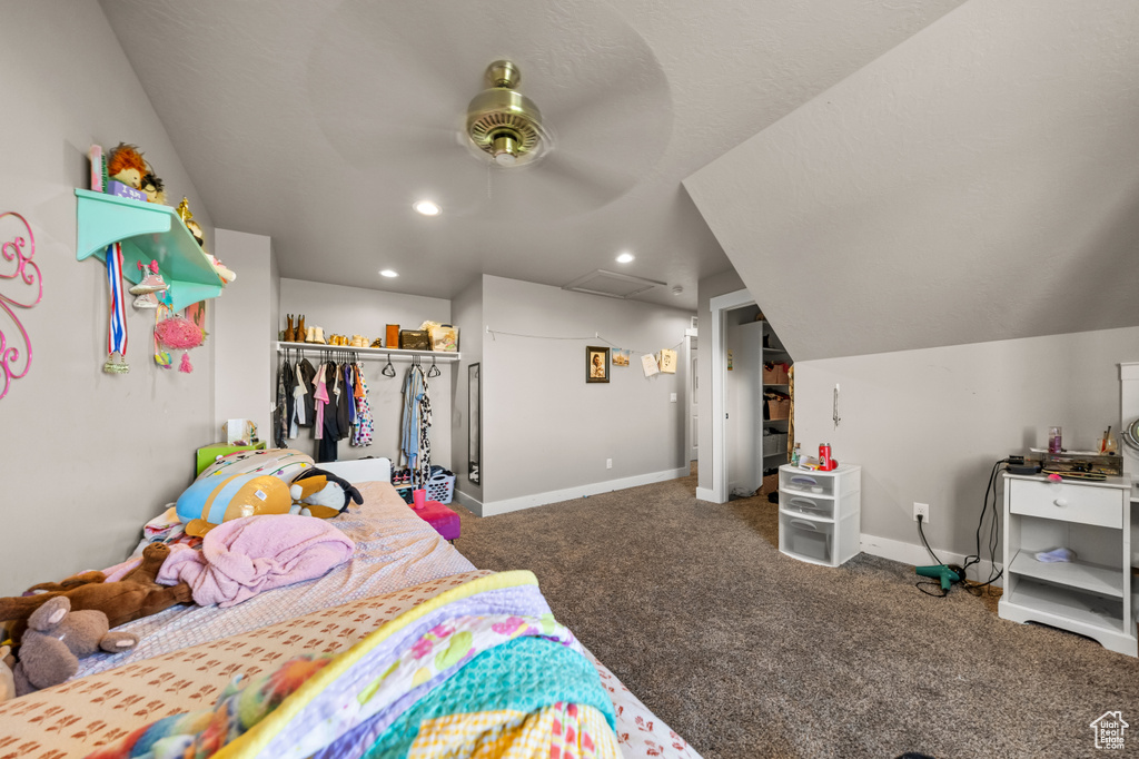 Bedroom with a closet, ceiling fan, lofted ceiling, and dark colored carpet
