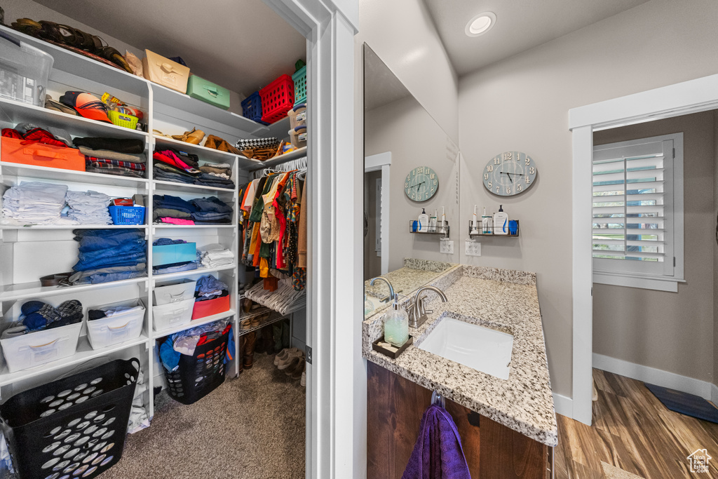 Spacious closet featuring dark colored carpet and sink