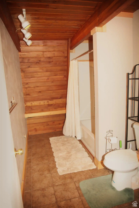 Bathroom featuring shower / bath combo, toilet, beamed ceiling, tile flooring, and wood ceiling