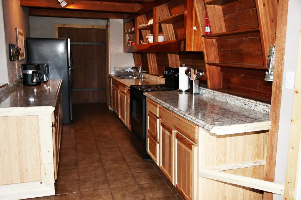 Kitchen with dark stone counters, dark tile flooring, black appliances, and sink